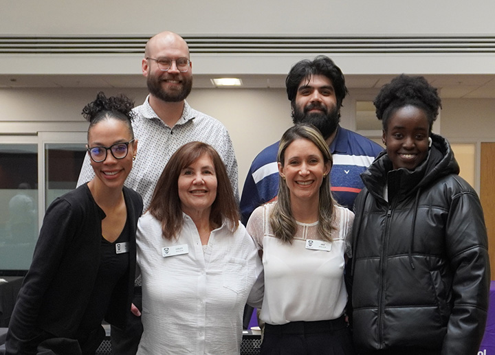 A diverse group of faculty and staff posing for a photo with arms around each other